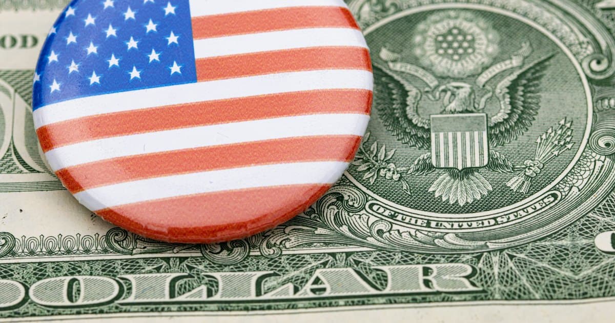 A round American flag campaign button lying on a U.S. one dollar bill.